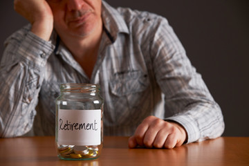 Depressed Man Looking At Empty Jar Labelled Retirement