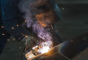 Welder man welding, spark, light and hot.  Mask and gloves for protection.