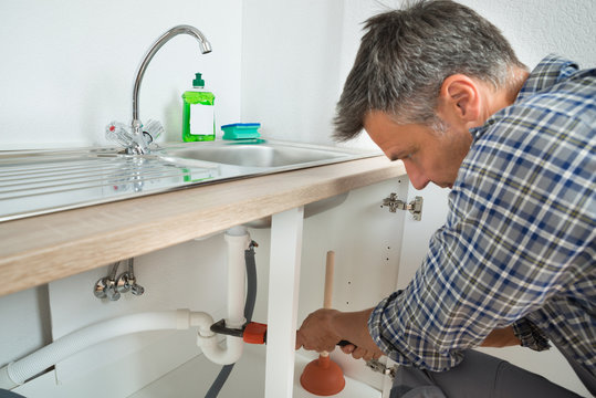 Plumber Fixing Sink Pipe In Kitchen