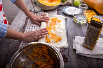Woman in kitchen making prepares a pie with pumpkin, selective focus