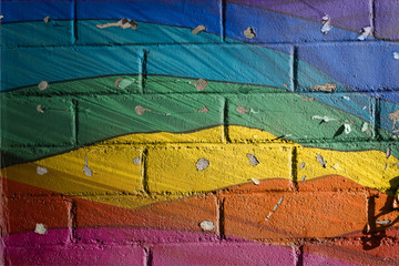 Rainbow painted peeling brick wall.