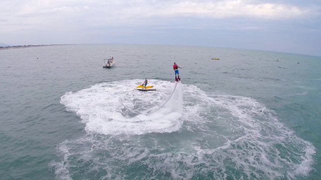 Aerial view of a man on Flyboard water jetpack and jetski