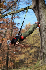 outdoor suspension training in forest - caucasian  man at tree