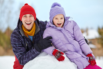 Father and daughter with snowman