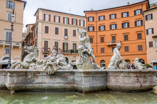 The sculptures on the fountain of Neptune in the Piazza Navona between historical colorful houses in Rome, Italy