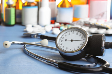 stethoscope with pills and bottle with the cure for the common cold on a blue table on a white background