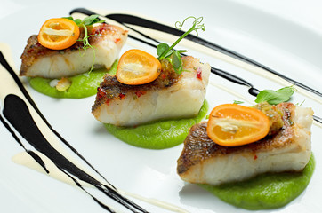 Delicious fish served on white dish, decorated with salad and sauce
