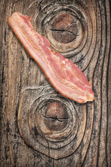 Bacon Rasher on Old Knotted Wood Background