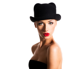 Fototapeta na wymiar Fashion portrait of a beautiful young girl wearing a black hat.