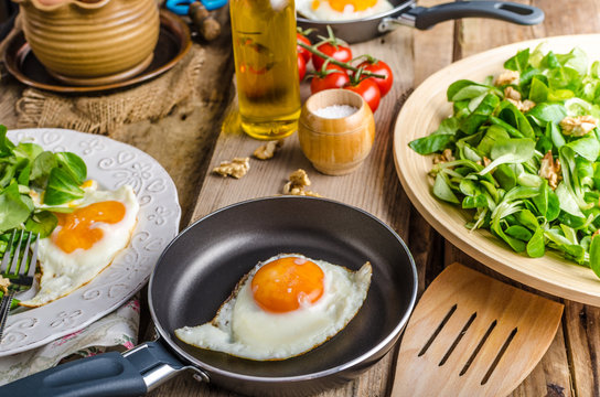Fried eggs with salad and nuts