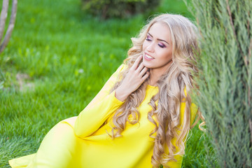 Naklejka premium Happy blonde woman sitting outdoors at summer Field