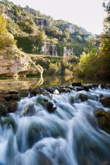 Fototapeta na wymiar Anapo river flowing in the Pantalica valley, Sicily, and the walls of the canyon in the background
