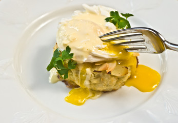 Almond Crab and poched egg on white plate with fork percing eeg