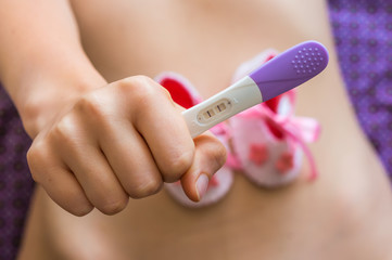 Pregnant woman holding a pregnancy test