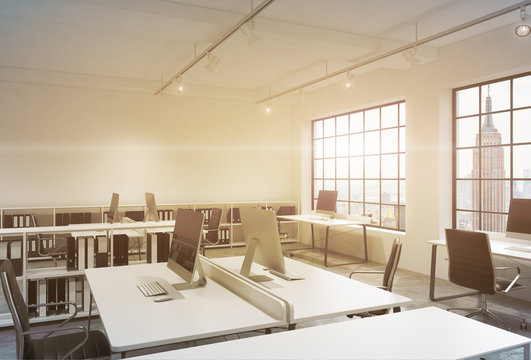 Workplaces in a sunset loft open space office. Tables are equipped with computers; book shelves. New York panoramic view. A concept of a high quality consulting services. Toned image. 3D rendering.