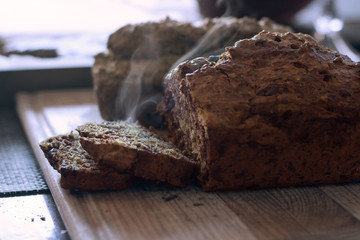 Home made zucchini bread sliced and steaming on a cutting board two loaves