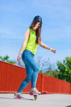 Teen girl skater riding skateboard on street.