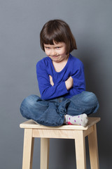 kid wellbeing concept - funny preschool child sitting with crossed legs and arms ready to make cute silly things,studio shot