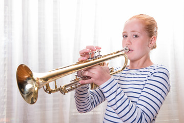red haired teenage girl playing the trumpet