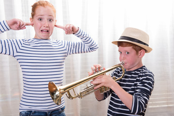 boy with hat is playing the trumpet - sister annoyed