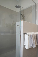 Bathroom interior in neutral tone with tiles, shower head and towels.
