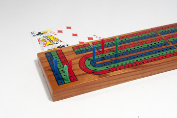Cribbage board with red, green and blue pegs against a white background