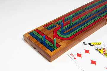 Cribbage board with red, green and blue pegs against a white background