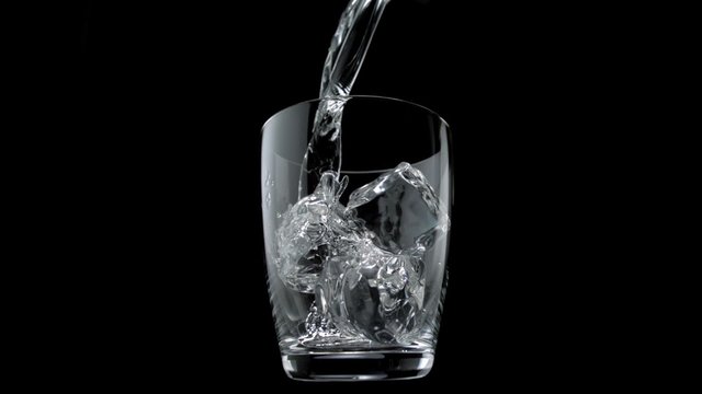 Pouring water into glass with ice cubes shooting with high speed camera, phantom flex.