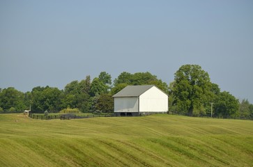 Obraz premium Barn and horse corral on a distant hill in a freshly cut pasture