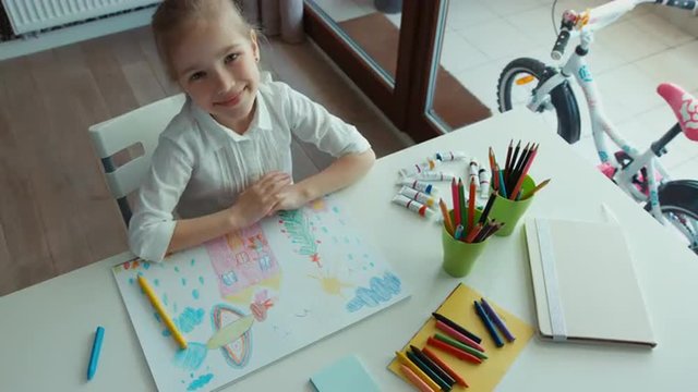 Preschooler girl laughing. Portrait child painting a picture. Looking at camera. Thumbs up. Ok. Top view