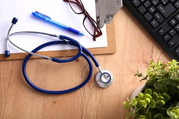 A medical stethoscope near a laptop on a wooden table, on white