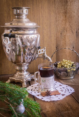 Tea in glass with coaster and russian samovar on wooden background. Home christmas decoration