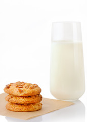 Stack of three homemade peanut butter cookies on baking paper and glass of milk, isolated on white background