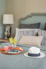 hat and tray with glass vase flower on bed