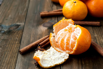 tangerines, oranges and cinnamon sticks on a wooden table