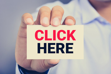 CLICK HERE message on the card held by a man hands