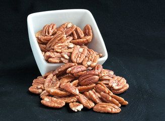 Noix de pécan dans une coupelle sur fond noir