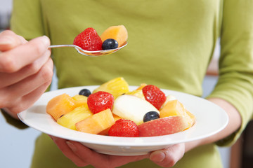 Close Up Of Woman Eating Bowl Of Fresh Fruit