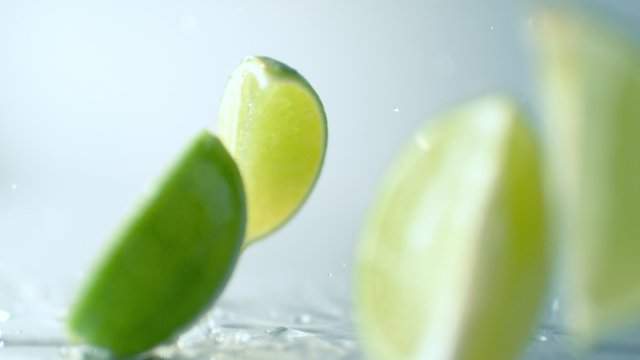 Camera follows a lime falling into wedges on wet surface. Shot with high speed camera, phantom flex 4K. 4K 30fps. Slow Motion.