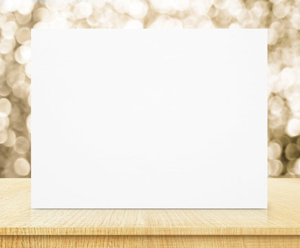 White Poster With Sparkling Gold Bokeh Wall And Wooden Table, Bu