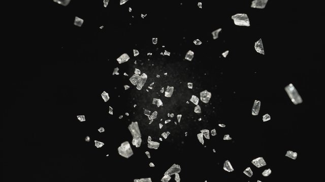 Pieces of glass fly after being exploded against black background. Shot with high speed camera, phantom flex 4K. 4K 30fps. Slow Motion.