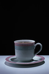 белая чашка с блюдцем на черном фоне