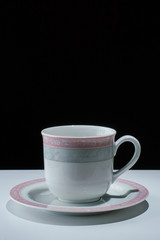 белая чашка с блюдцем на черном фоне