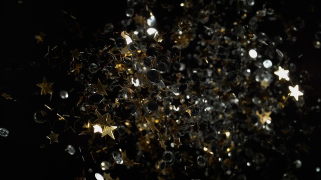 Star and round shape confetti fly after being exploded against black background. Shot with high speed camera, phantom flex 4K. 4K 30fps. Slow Motion.