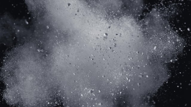 White powder/particles fly after being exploded against black background. Shot with high speed camera, phantom flex 4K. 4K 30fps. Slow Motion.