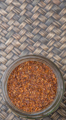 Obraz na płótnie Canvas Dried rooibos herbal tea in mason jar over wicker background