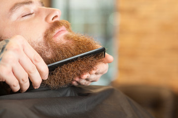 Skillful male hairstylist is working with comb