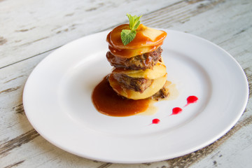 Calf's liver with apples Laid layers with sauce on a white plate
