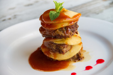 Calf's liver with apples Laid layers with sauce on a white plate