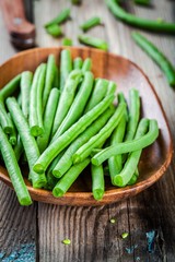 pods of fresh organic green beans in a wooden bowl closeup